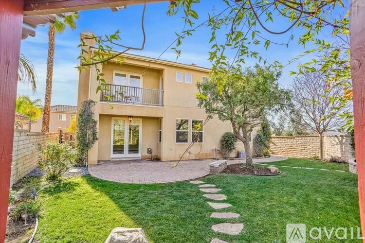 A house with a balcony and a tree in the front yard.