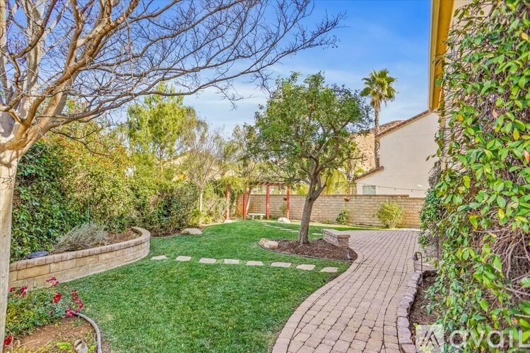 A backyard with a brick walkway and a green lawn.