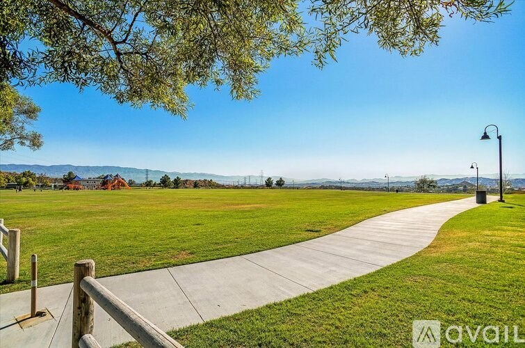 A park with a walking path and a fence.