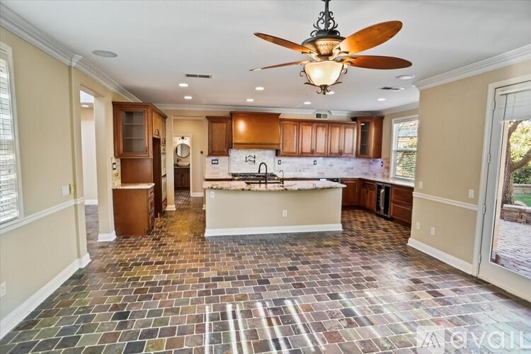 A spacious kitchen with a fan and tile flooring.