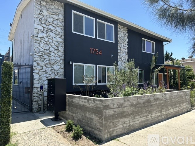 A modern house with a stone wall and a black front door.