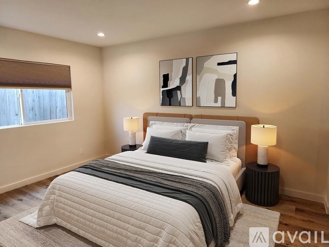 A bedroom with a large bed and two lamps.