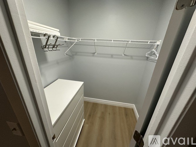 A white closet with a wooden floor and a white dresser.