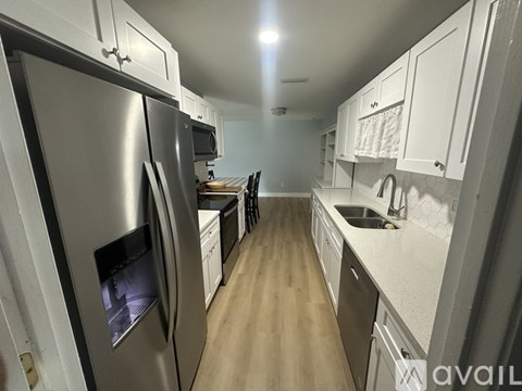 A kitchen with a refrigerator on the left and cabinets on the right.