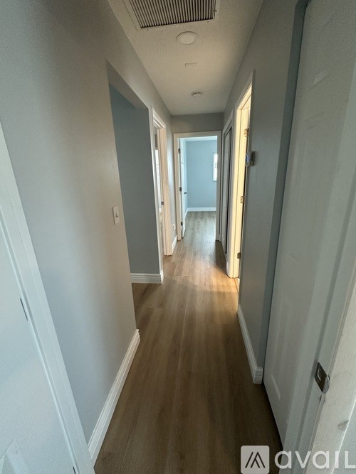 A long hallway with light coming through the door at the end.