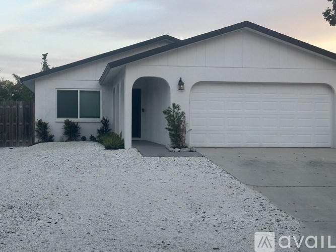 A house with a white garage door and a gravel driveway.