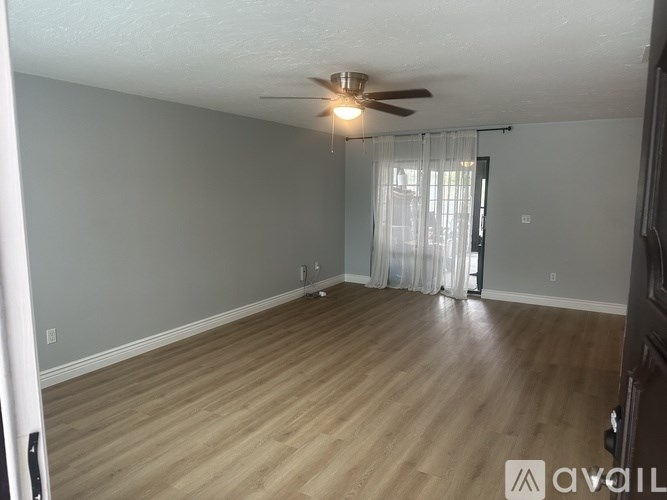 A room with a ceiling fan and wooden flooring.