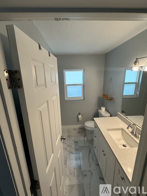 A bathroom with a toilet, sink, and mirror.
