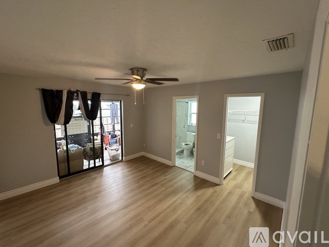 A spacious room with wood flooring and a ceiling fan.