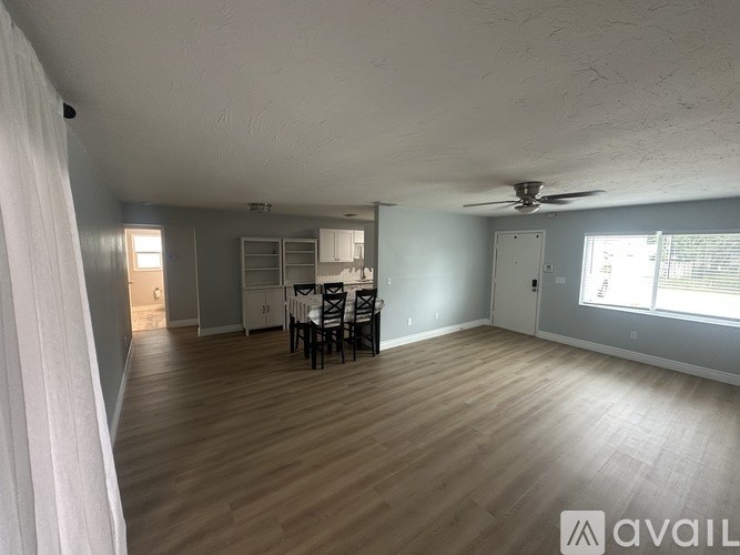 A room with wooden flooring and a dining table set up.