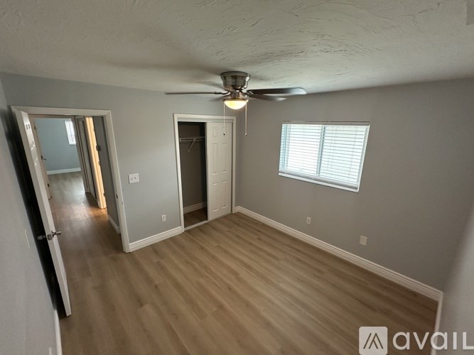 A room with a ceiling fan and a window with blinds.