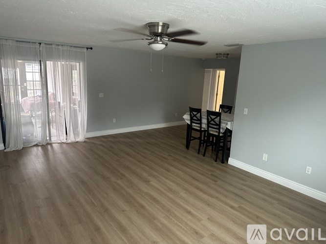 A room with a ceiling fan and wooden flooring.
