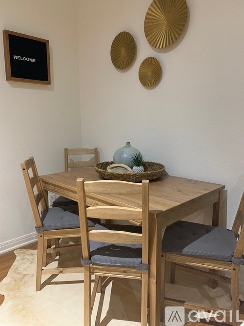 A wooden dining table with four chairs and a decorative wall piece.