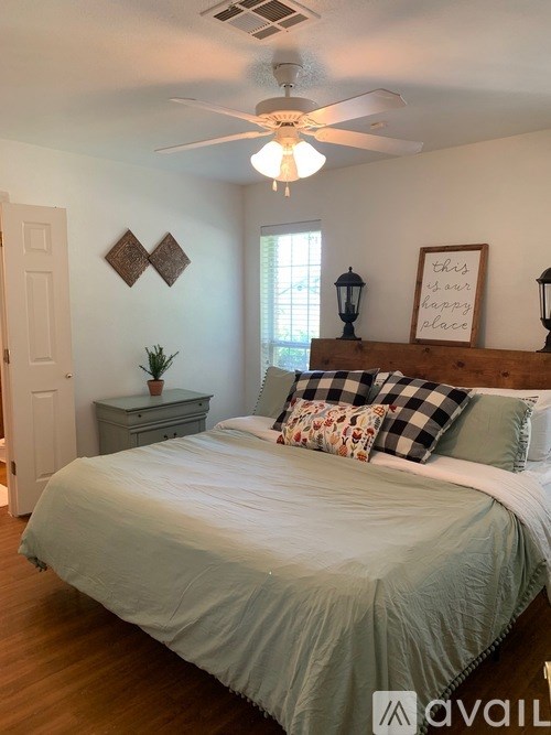 A bedroom with a bed, dresser, and a ceiling fan.