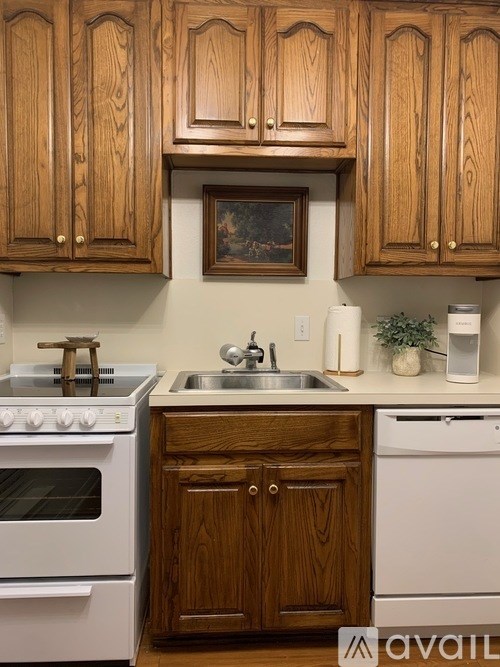 A kitchen with wooden cabinets and a white stove top oven.