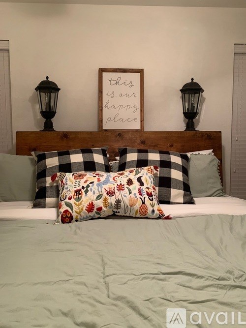 A bed with a wooden headboard and a sign above it that says "this is our happy place".