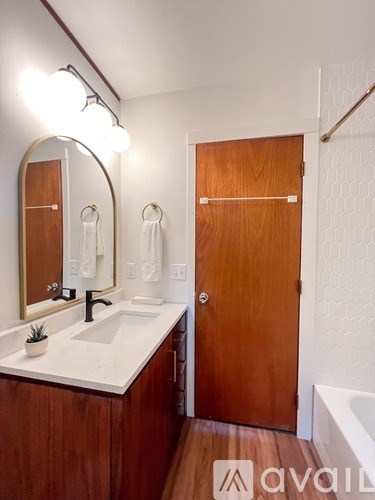 A bathroom with a sink, mirror, and wooden door.