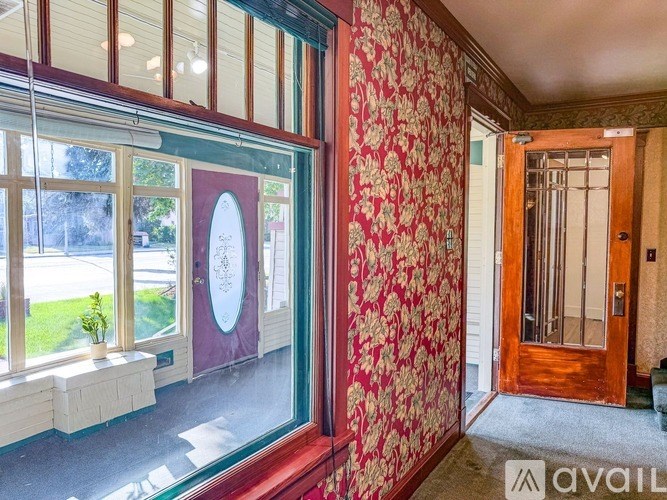 A room with a red wallpaper and a wooden door.