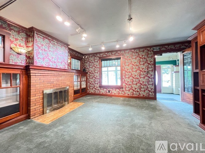A room with floral wallpaper and a fireplace is available for rent.