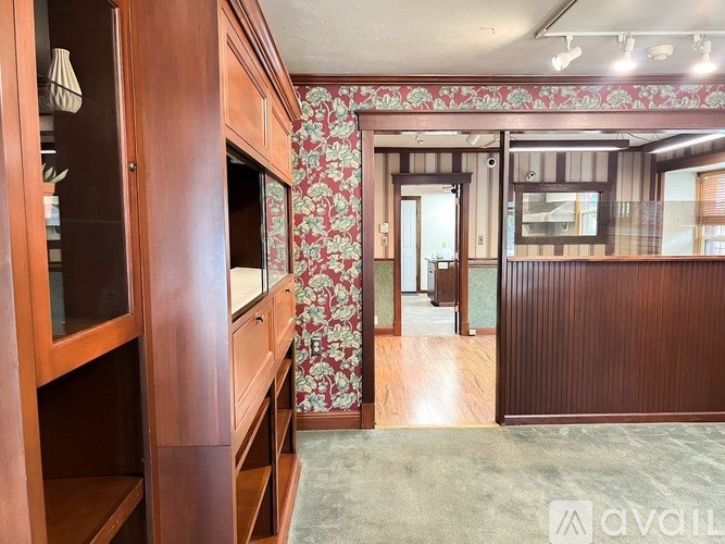A room with wooden furniture and floral wallpaper.