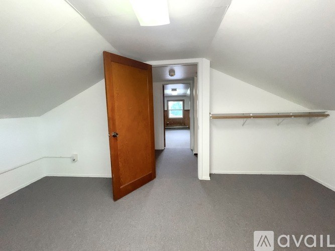A room with a wooden door and a white wall.