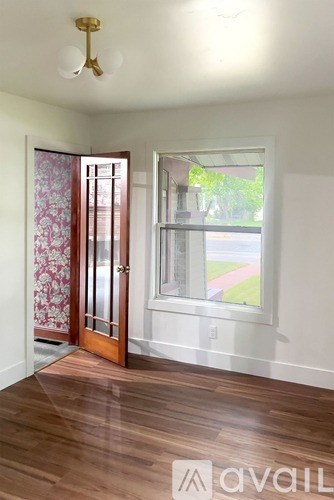 A room with a wooden floor and a window with a view of a street.