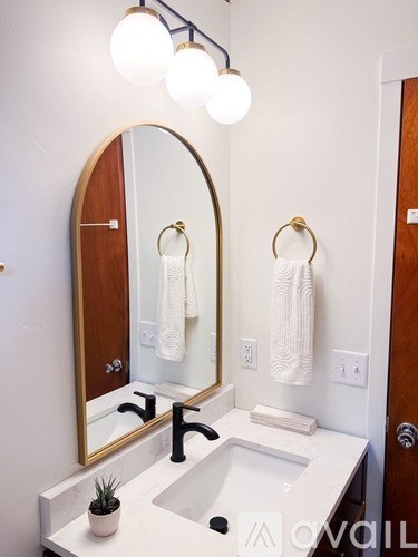 A bathroom with a sink, mirror, and lights.