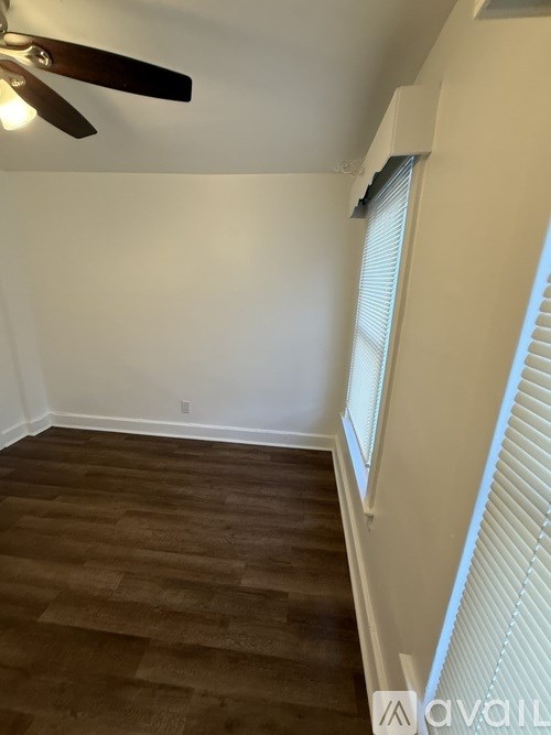 A room with a ceiling fan and wooden flooring.