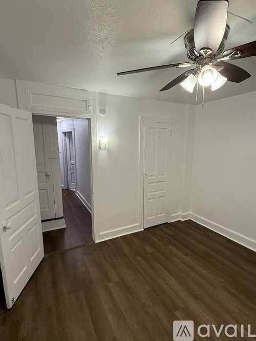 A room with a ceiling fan and wooden floors.