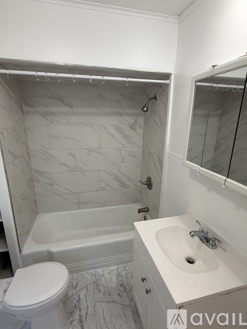 A white bathroom with marble tiles and a white toilet.