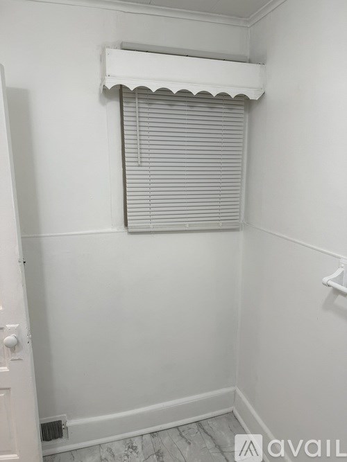 A bathroom with a window covered by a white blind.
