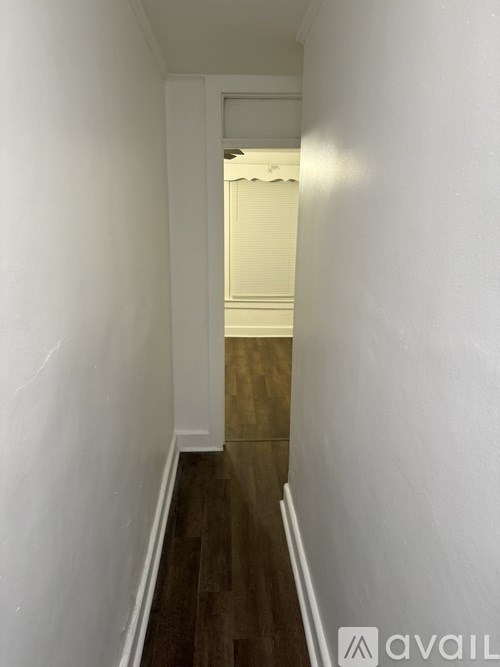 A long hallway with wood floors and white walls.