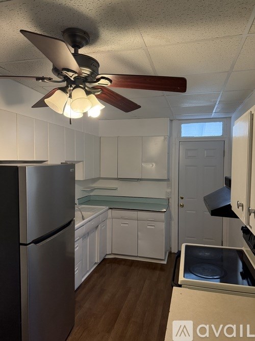 A kitchen with a refrigerator, a ceiling fan, and a window.