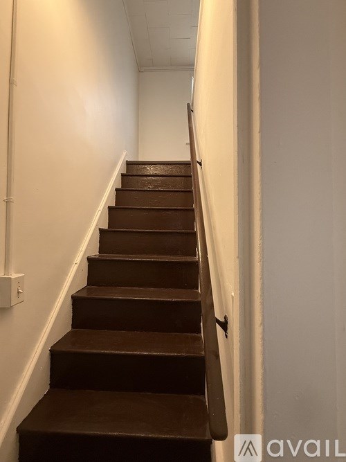 A staircase with a black handrail and wooden steps.