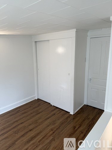 A room with a white door and a wooden floor.