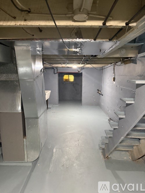 A dimly lit industrial hallway with a staircase on the right and a door on the left.