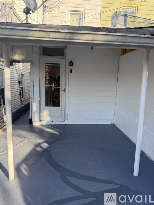A white door is on the left side of a covered porch.