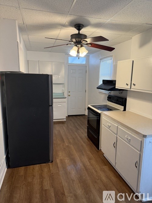 A kitchen with a black refrigerator and white cabinets.