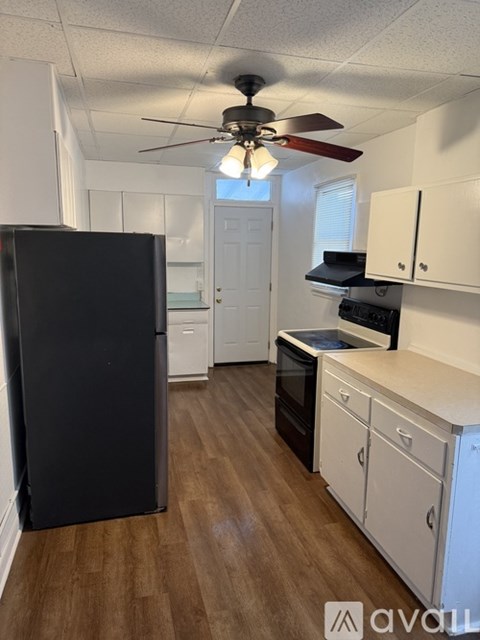 A kitchen with a black refrigerator and white cabinets.