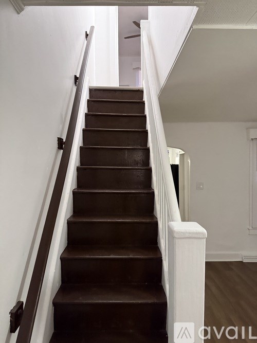 A staircase with white railings and brown steps.