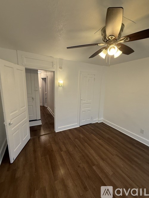 A room with a ceiling fan and wooden flooring.