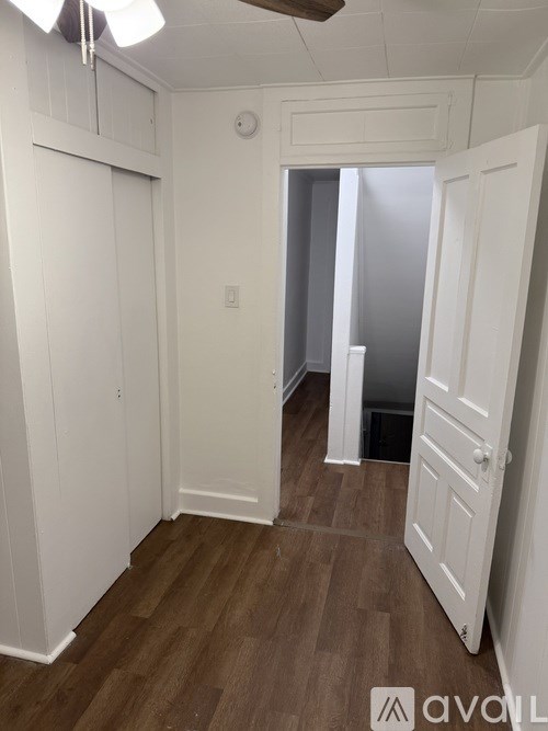 A hallway with a white door on the right and a white wall on the left.