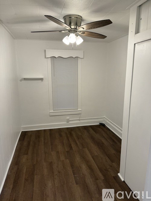 A room with a ceiling fan and a window with blinds.