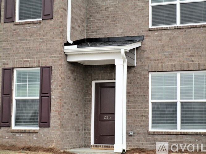 A brick house with a brown door and windows with white frames.