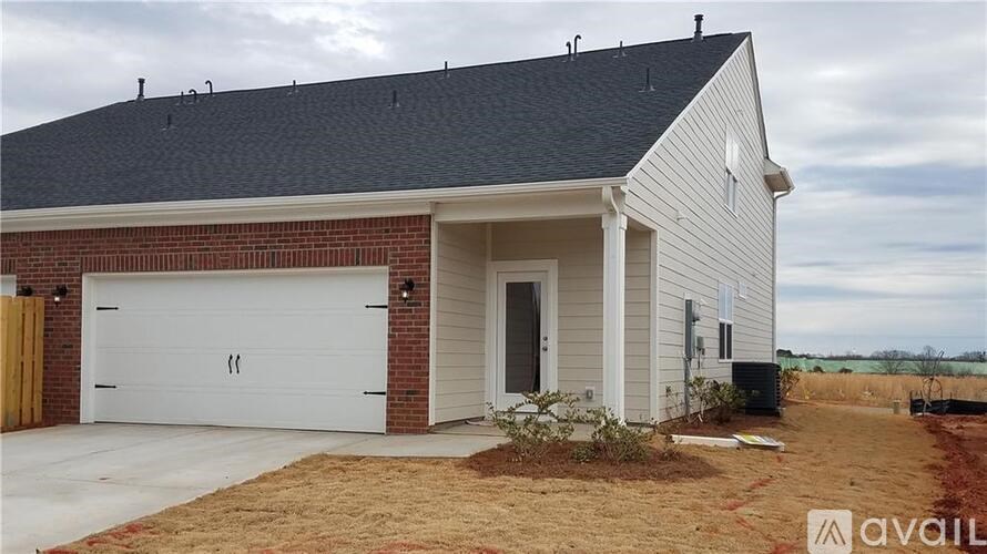 A two-car garage is attached to a white house with a brick chimney.