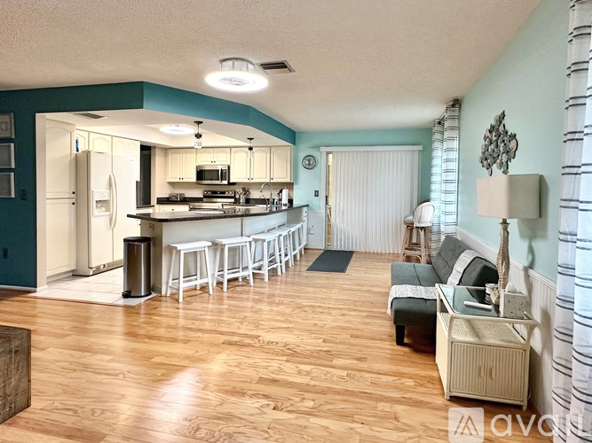A kitchen with a refrigerator, stove, and bar stools.