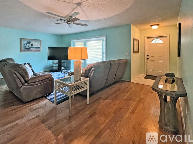 A living room with a brown couch, a brown chair, and a wooden coffee table.