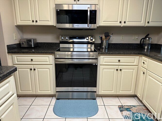 A kitchen with white cabinets and a black countertop.