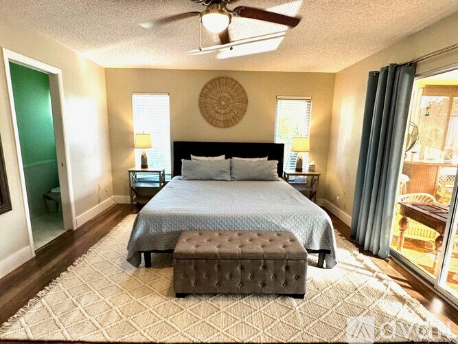 A bedroom with a bed, bench, and ceiling fan.