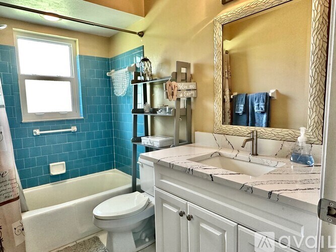 A bathroom with blue tiles and a white toilet.